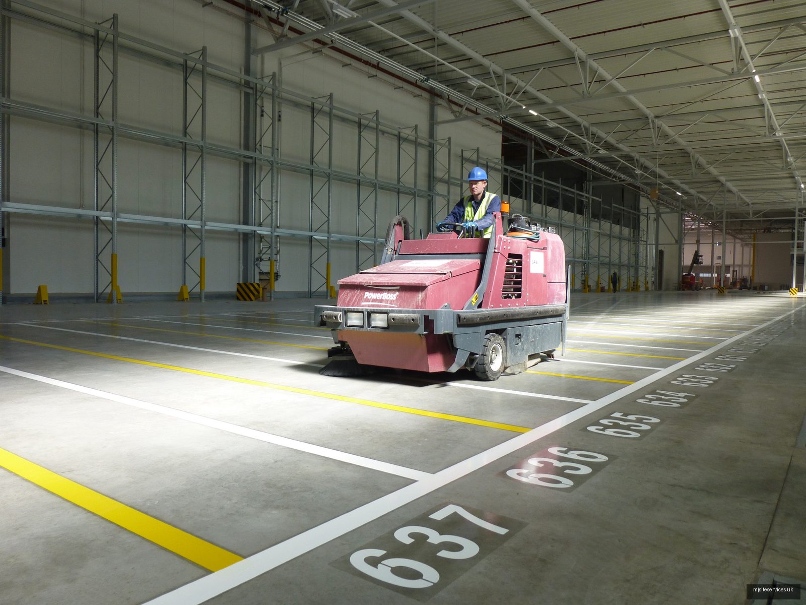 Ride-on floor scrubber cleaning industrial flooring